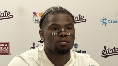 Kamario Taylor of Mississippi State speaking at a press conference in front of a Bulldogs backdrop